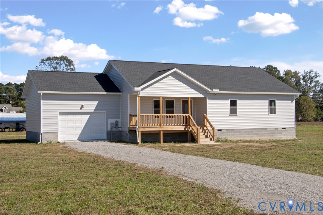 Single-story residence featuring light-colored siding, a covered wooden front porch, an attached one-car garage, and a gravel driveway