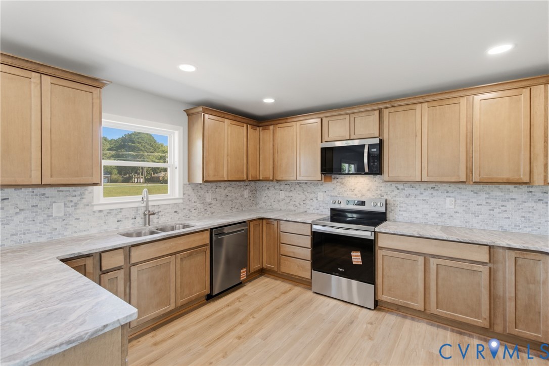 Kitchen featuring shaker-style wood cabinetry, stone-finish countertops, mosaic tile backsplash, stainless steel appliances, and wood-finish flooring