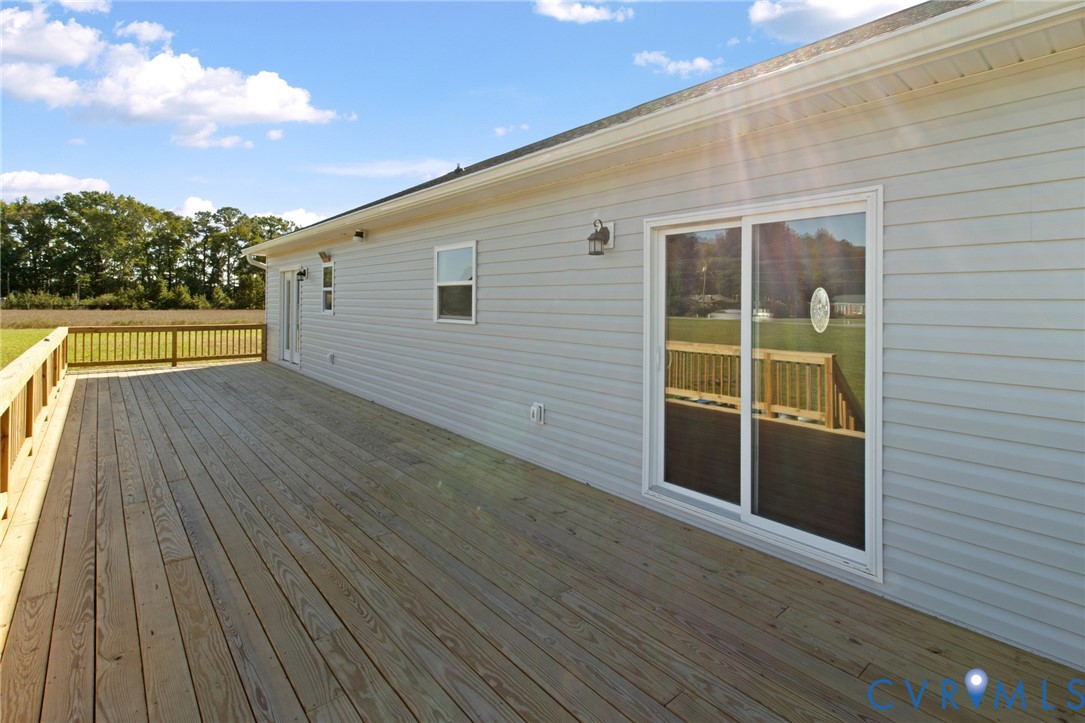 Expansive wooden deck featuring horizontal siding, sliding glass doors, and wooden perimeter railing