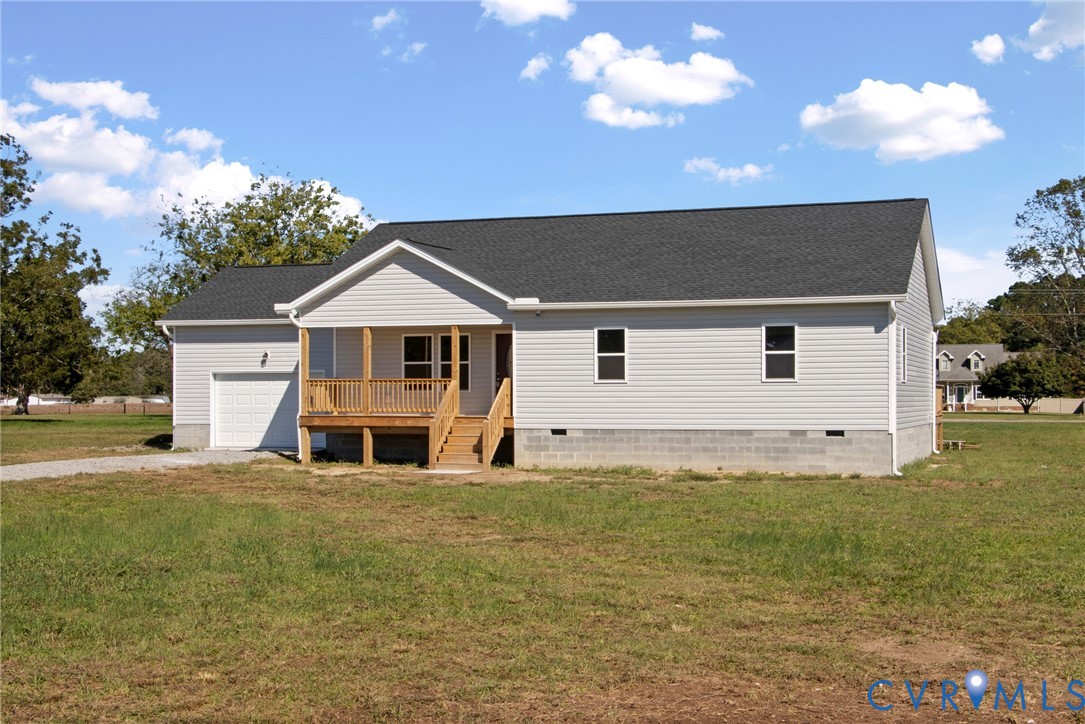 Single-story residence featuring horizontal vinyl siding, an asphalt shingle roof, a front-facing attached garage, and a covered wooden porch