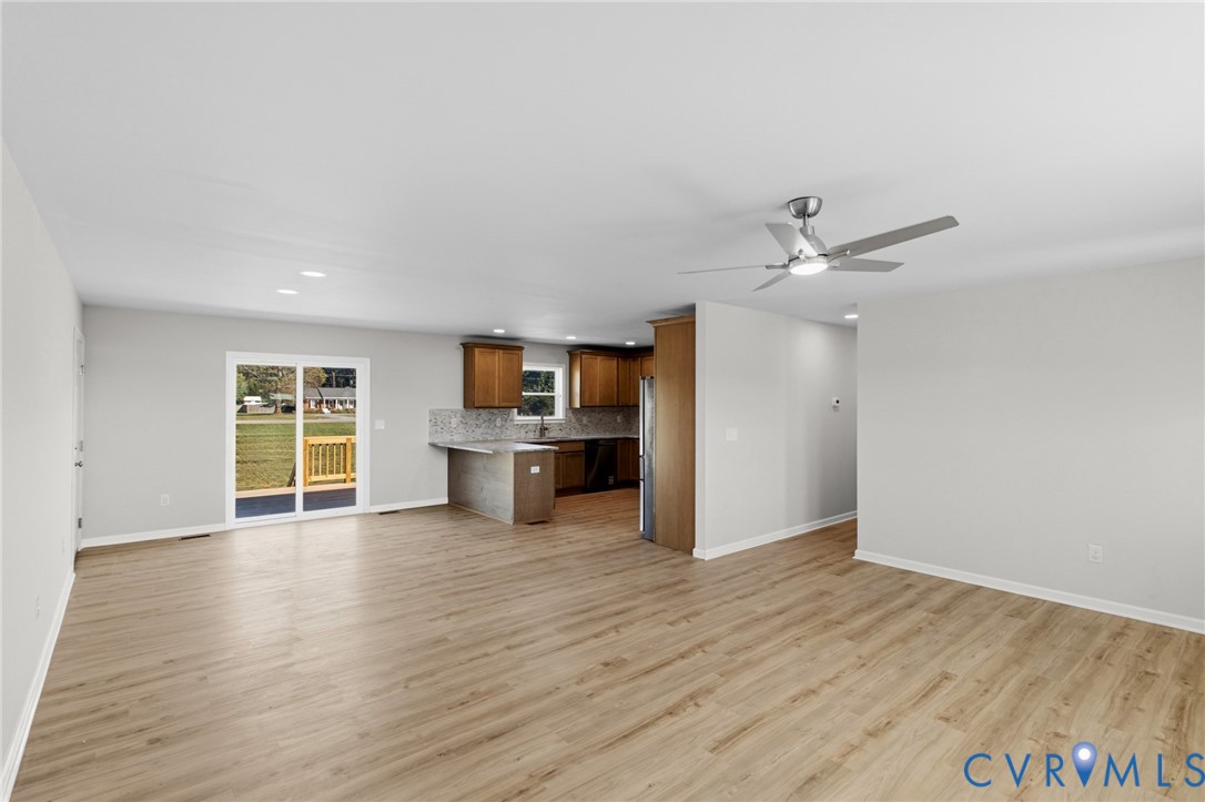 Wood-finish flooring, recessed lighting, ceiling fan, wooden cabinetry, and glass sliding door