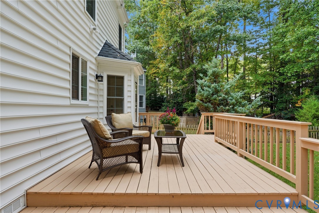 Raised exterior wood deck with vertical baluster railing and light-toned siding