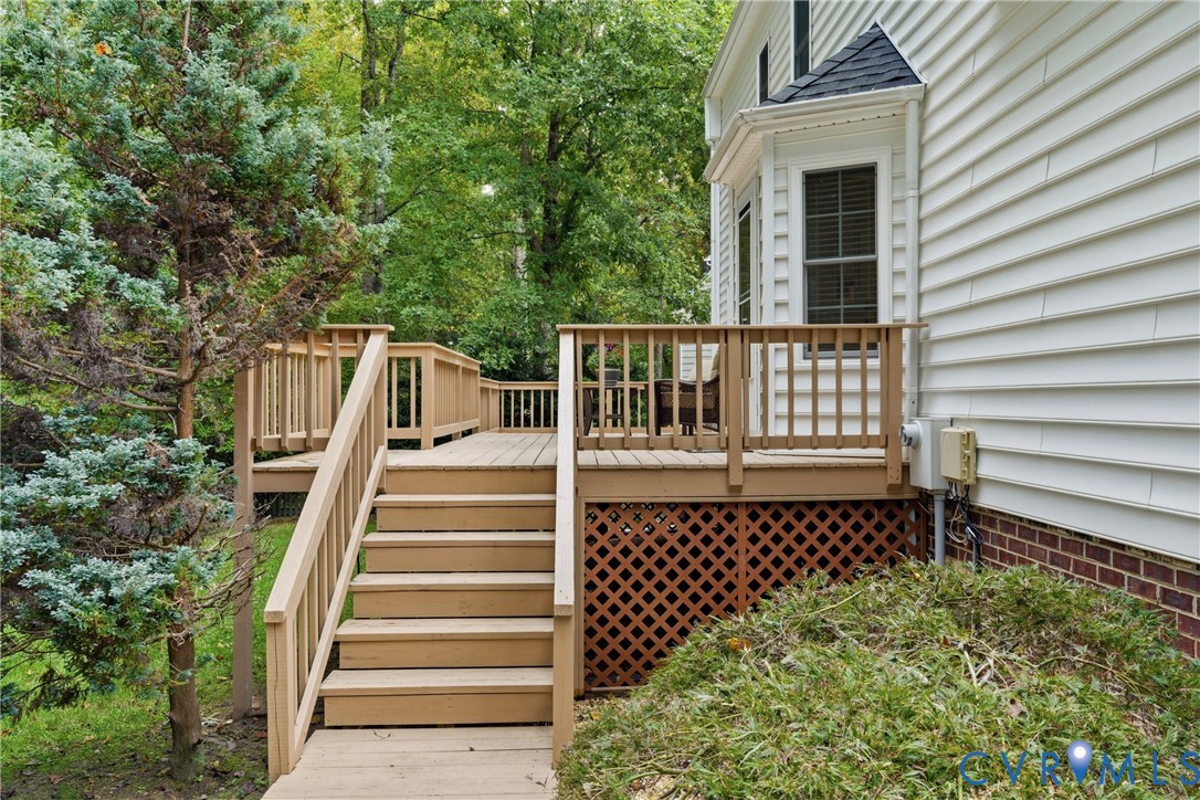 Raised wood deck featuring vertical balusters, staircase with handrails, and wood lattice skirting