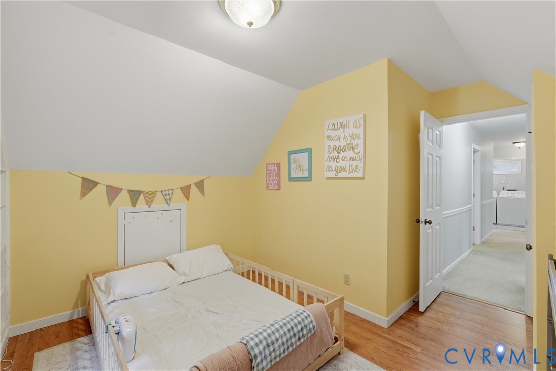 Vaulted ceilings, wood-finish flooring, and a flush-mount ceiling light fixture