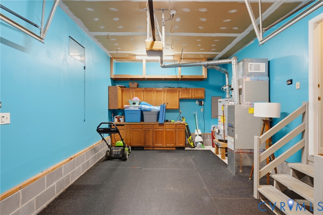 Garage featuring built-in wood cabinetry, overhead storage shelving, and a high-efficiency HVAC system