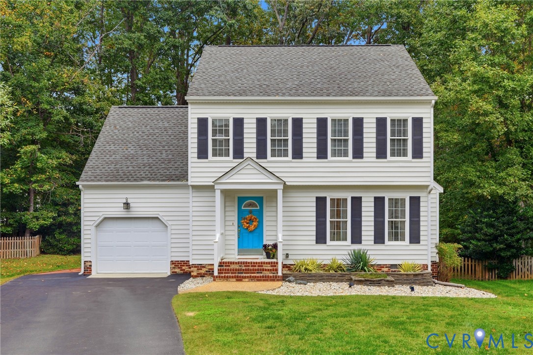 Two-story exterior featuring white horizontal siding, dark shutters, a brick-accented front entry, an attached garage, and stone-bordered landscaping