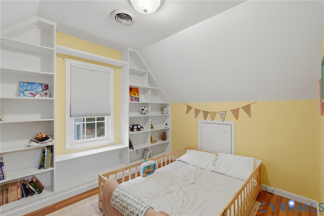 Built-in wall-to-wall shelving, multi-pane window, flush-mounted ceiling lighting, and wood-finish flooring