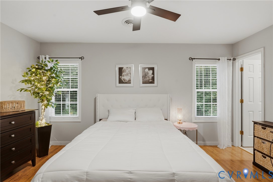 Room with hardwood flooring, dual windows with multi-pane glass, and a ceiling-mounted light fixture with a fan