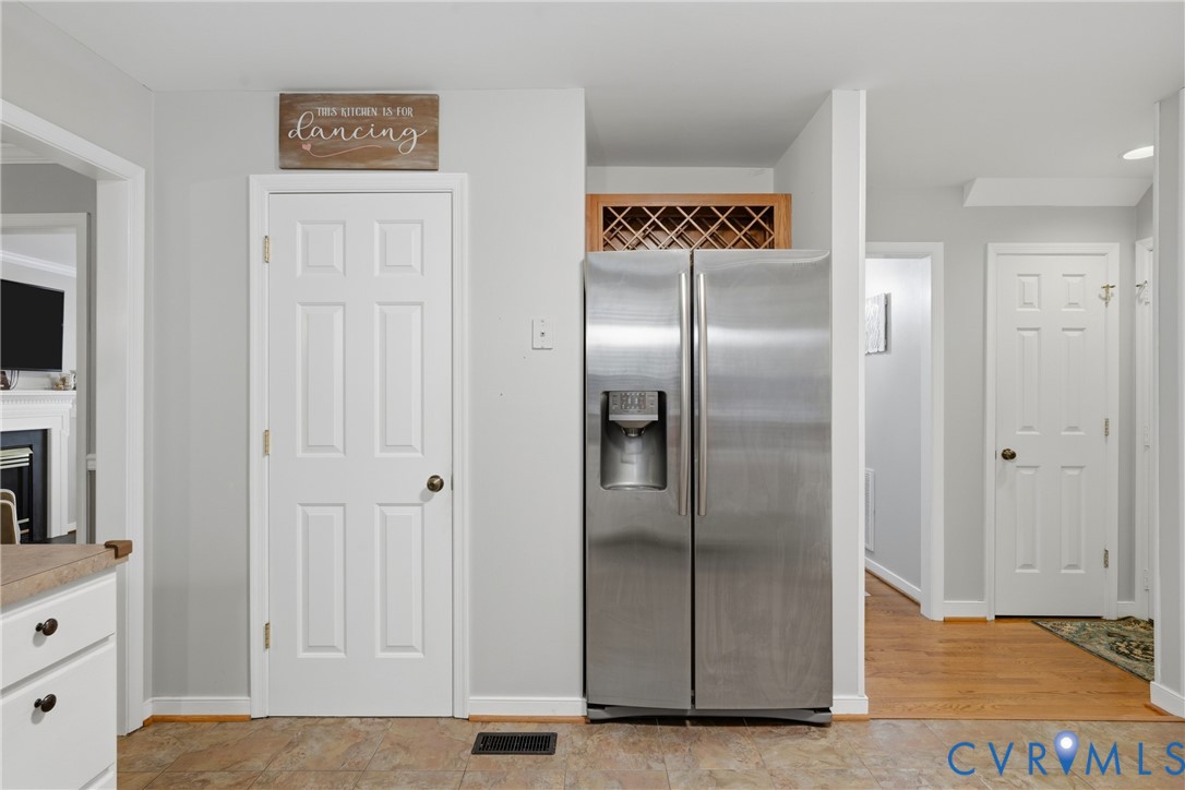 Stainless steel side-by-side refrigerator, built-in wooden wine rack, and solid-core paneled interior doors