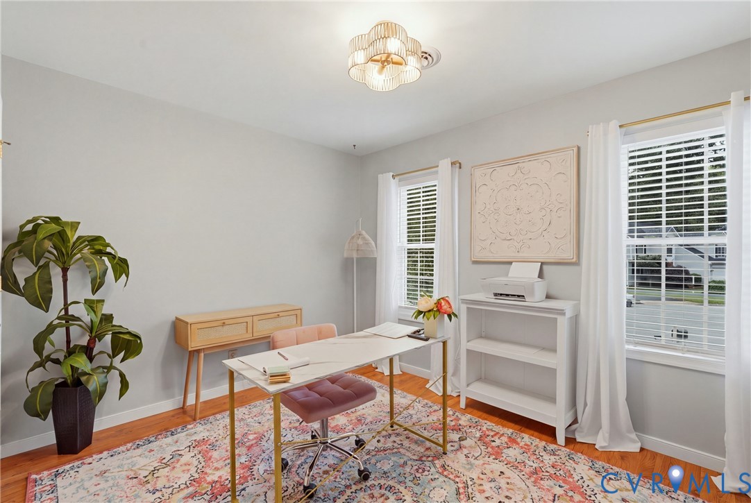Room interior featuring wood-finish flooring, dual windows with white horizontal blinds, and a multi-tiered flush-mount ceiling light fixture