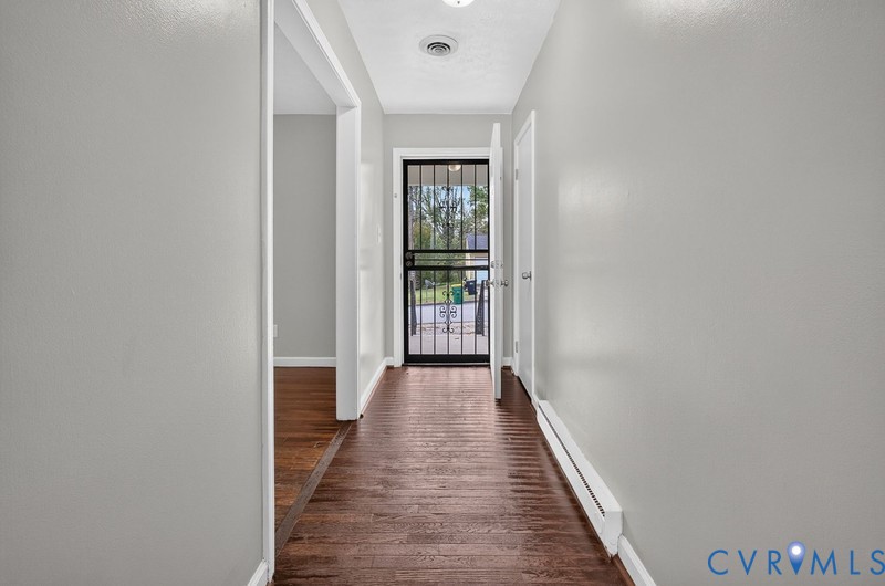 Entryway featuring wood-finish flooring, neutral wall paint, and a metal security storm door