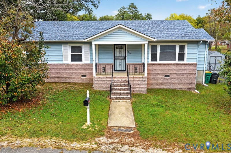 Single-story residence featuring blue horizontal siding, a lower brick facade, a covered front entryway with metal railings, and a shingled roof