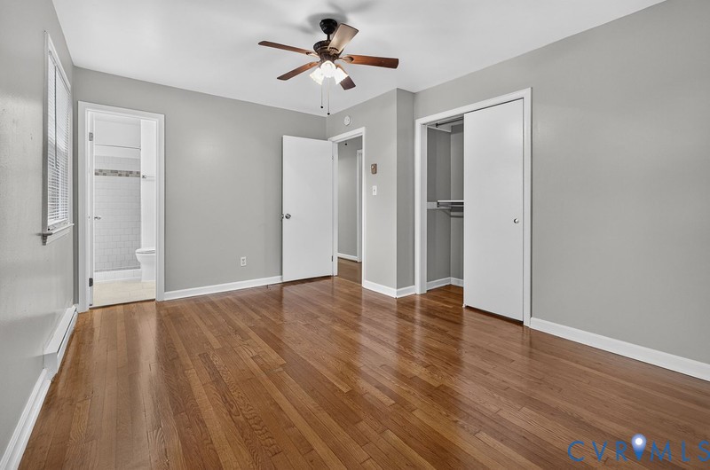 Room featuring wood-finish flooring, a ceiling fan with integrated lighting, and a reach-in closet with sliding doors