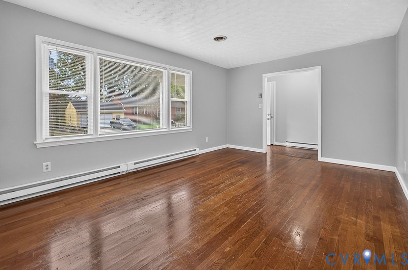 Room featuring wood-finish flooring, neutral wall paint, and a large multi-pane window