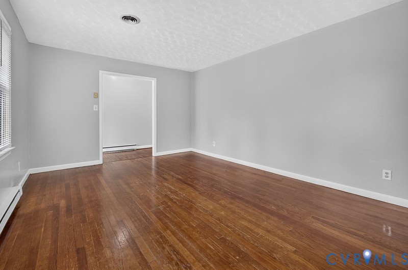 Neutral interior space featuring wood-finish flooring, light grey walls, and a textured ceiling