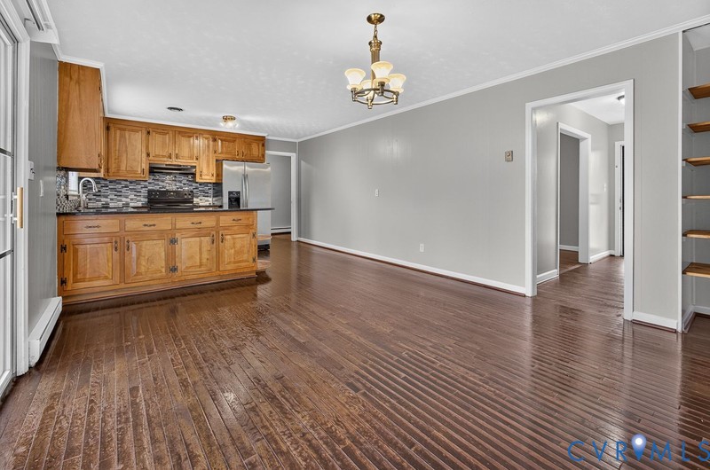 Open-concept interior featuring wood-finish flooring, oak cabinetry, a stone-tile backsplash, and built-in shelving