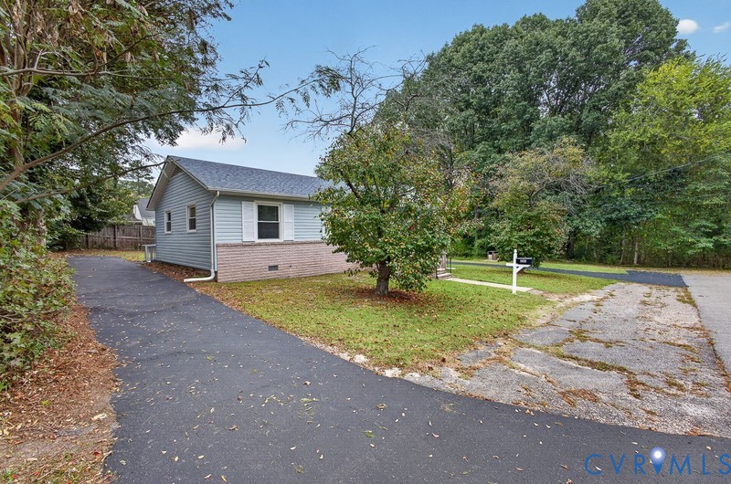 Exterior featuring light-blue horizontal siding, partial light-colored brick veneer, asphalt shingle roof, and an asphalt driveway