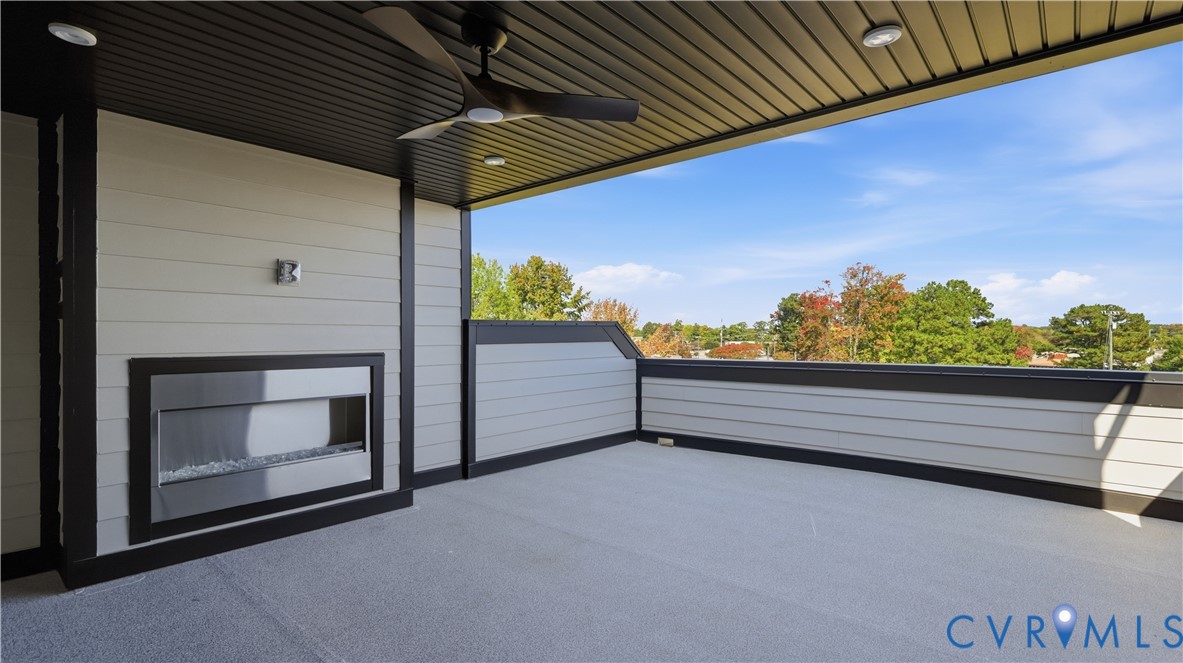 Covered balcony featuring horizontal lap siding, a built-in linear fireplace, a matte black ceiling fan, and recessed lighting