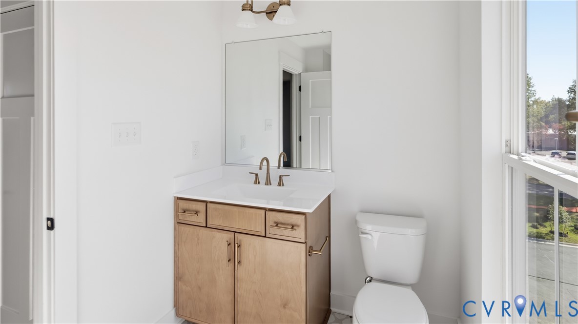 Vanity featuring light wood-finish cabinetry, a rectangular sink with a white surface, metal hardware, a wall-mounted mirror, and a dual-light fixture