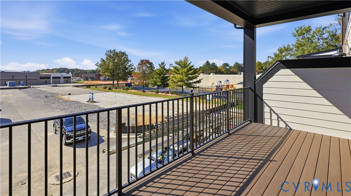 Covered exterior balcony featuring synthetic wood-finish decking and black metal railing