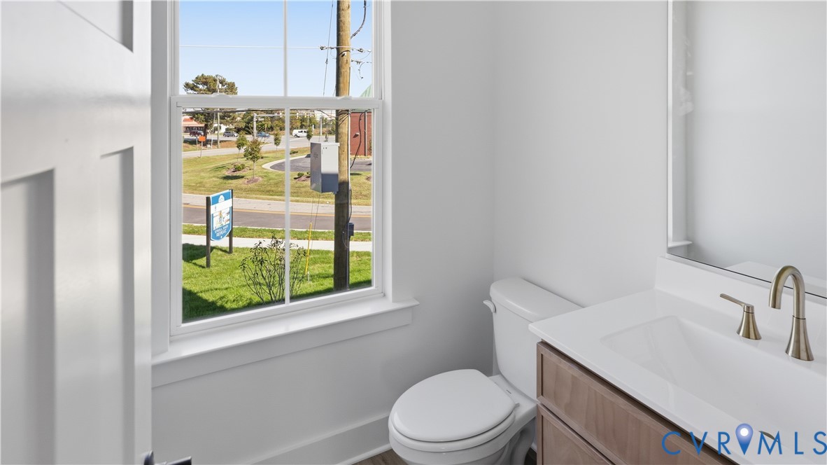 Single-hung window, white-finish vanity with countertop sink, metallic faucet, and wall-mounted mirror