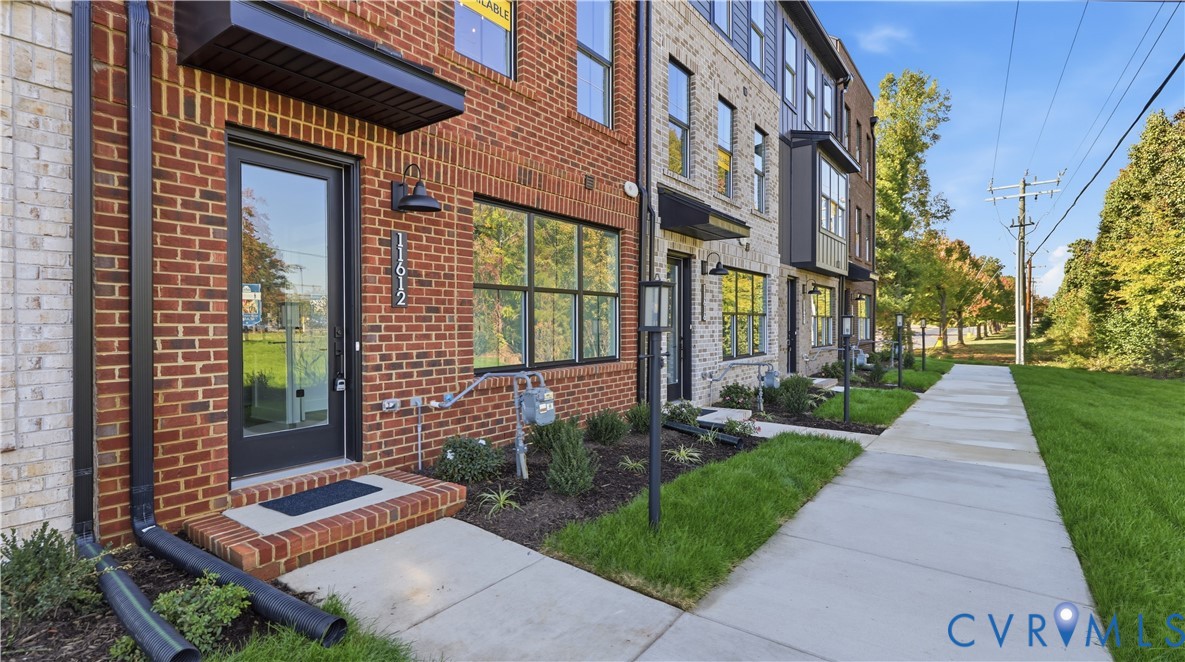 Brick and masonry facade featuring multi-pane windows, black metal awnings, and exterior wall-mounted lighting Brick and masonry facade featuring multi-pane windows, black metal awnings, and exterior wall-mounted lighting
