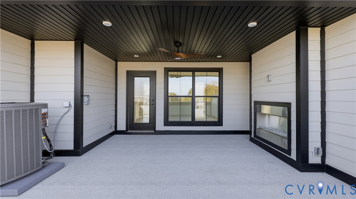 Covered outdoor patio featuring a black tongue-and-groove ceiling, recessed lighting, integrated ceiling fan, horizontal siding, and a linear built-in fireplace