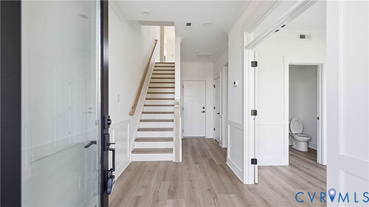 Entryway featuring wood-finish flooring, wainscoting, a staircase with a wooden handrail, and recessed lighting Entryway featuring wood-finish flooring, wainscoting, a staircase with a wooden handrail, and recessed lighting