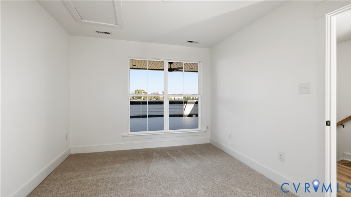 Neutral-toned wall-to-wall carpeting, dual-pane window with muntin bars, and ceiling attic access panel