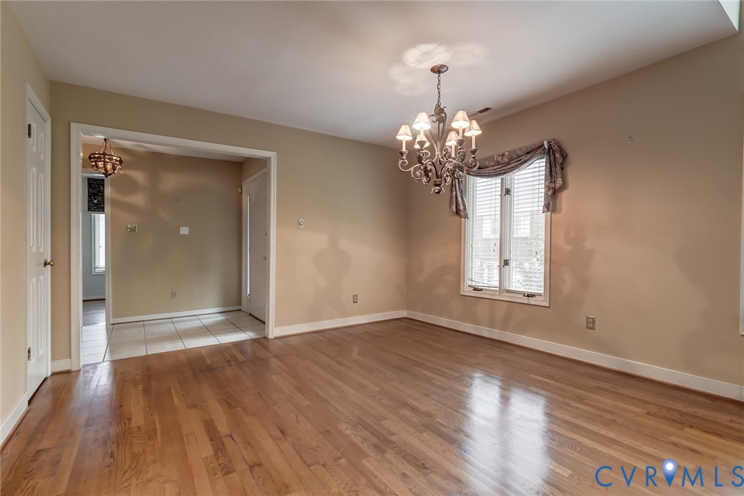 Hardwood flooring, multi-light decorative chandelier, multi-pane window with wood trim, and crown molding