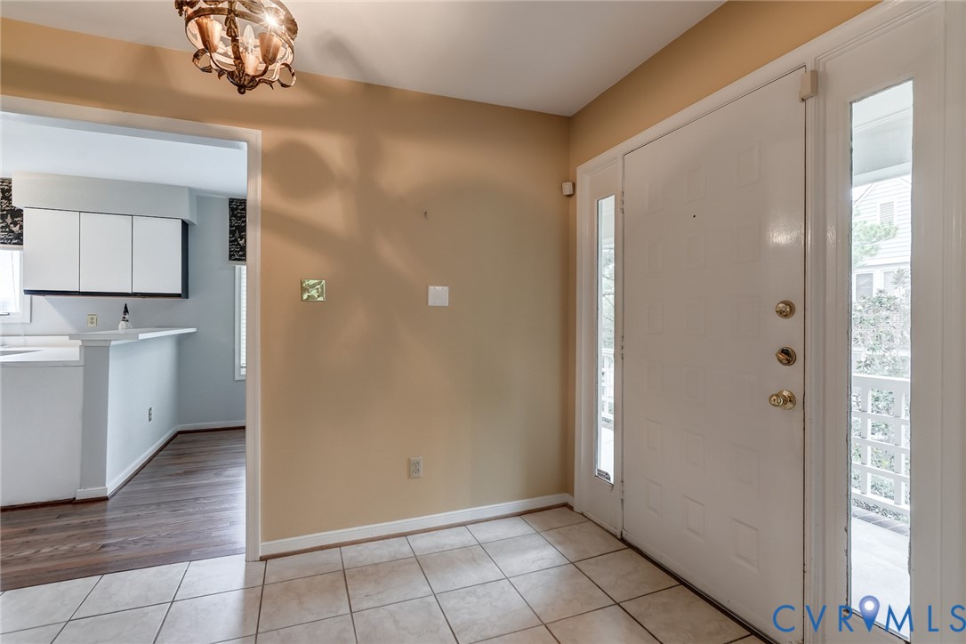 Entryway featuring tile flooring, a paneled door with side glass panels, and a multi-arm decorative light fixture