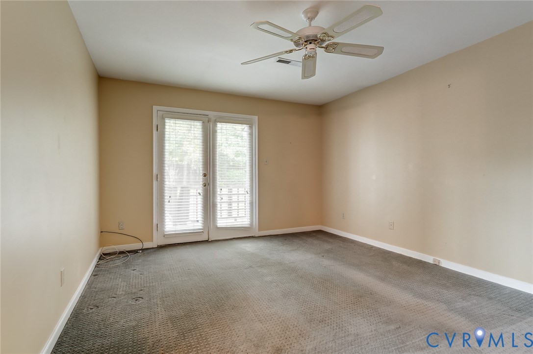 Room featuring carpeting, white ceiling fan, and double glass-paned doors with integrated blinds