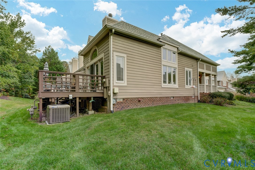 Exterior featuring horizontal siding, a brick foundation, arched window detailing, and a raised wooden deck