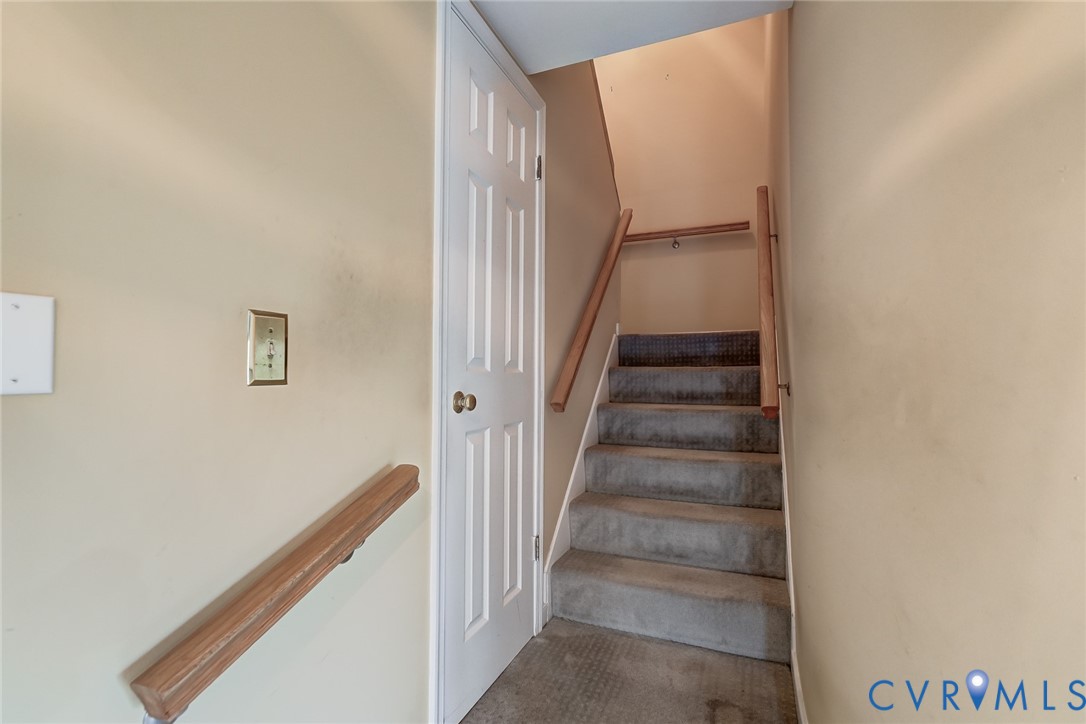 Staircase featuring wall-mounted wood handrails and a six-panel door
