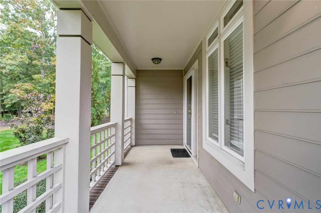 Covered porch featuring horizontal lap siding, square structural columns, white latticed railing, and tall windows