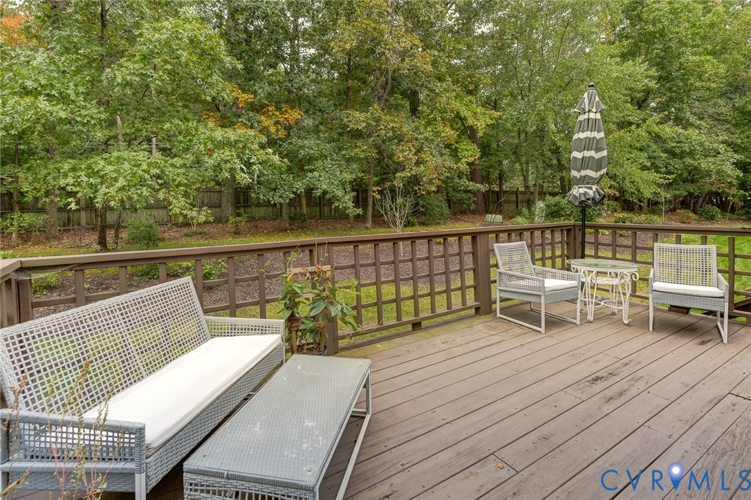 Elevated wood-plank deck featuring a lattice-style perimeter railing and a backdrop of mature, dense trees