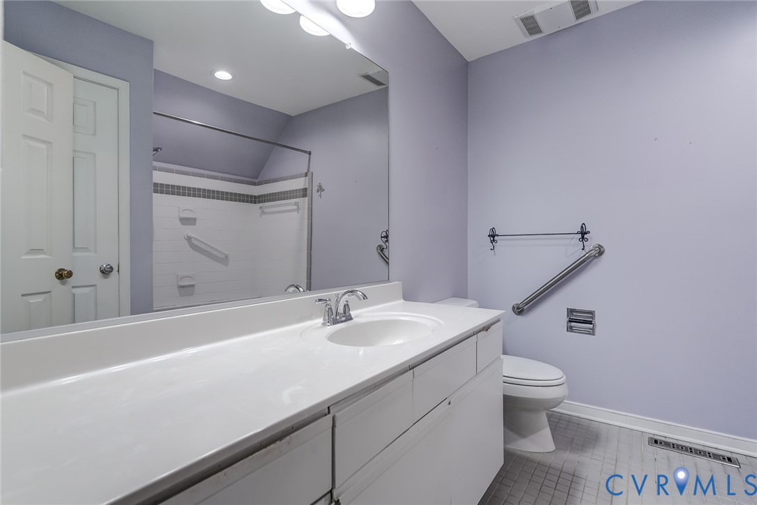 Full-width vanity with a solid-surface countertop, integrated basin, large wall-mounted mirror, and tile flooring