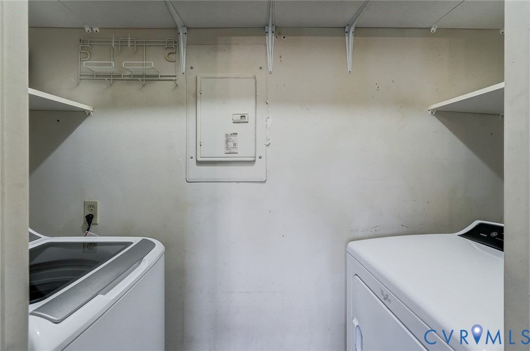 Dedicated laundry area featuring dual white open-frame wall shelves and a recessed electrical service panel
