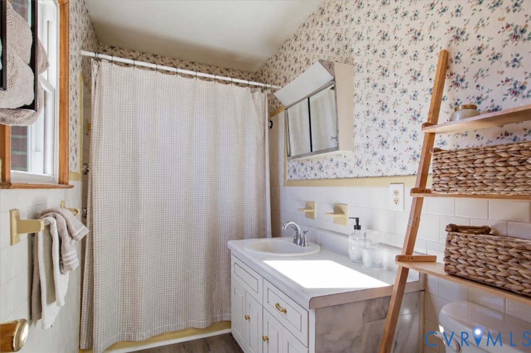 Bathroom featuring a white vanity cabinet with an integrated sink, a built-in recessed medicine cabinet, classic subway tile wall surround, and a tub-shower combination