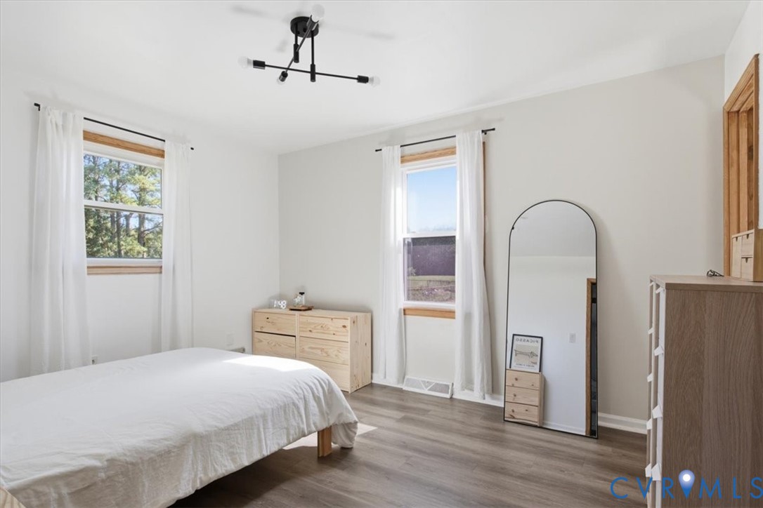 Wood-finish flooring, matte black multi-arm light fixture, and windows with natural wood trim