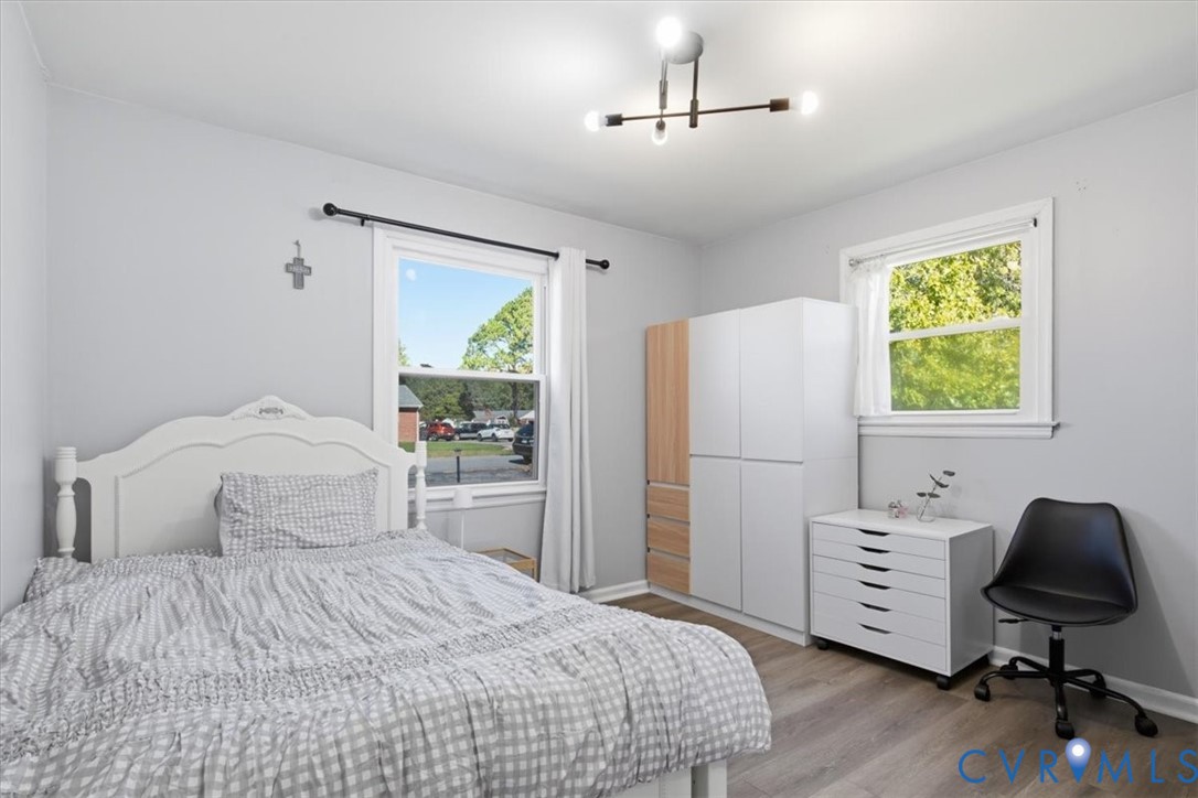 Neutral-toned interior featuring wood-finish flooring, dual windows with white casing, and a contemporary multi-arm sputnik chandelier