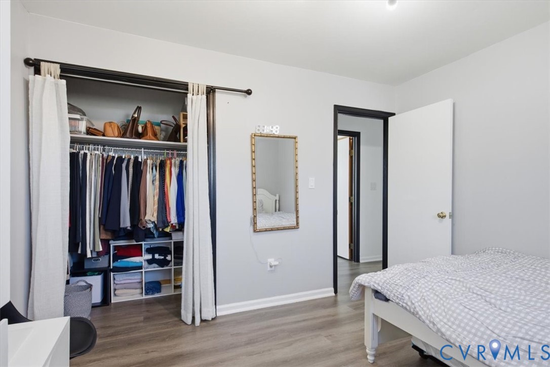 Room featuring wood-finish flooring, a sliding bypass closet track with wall-mounted rod, and contrasting black door frames