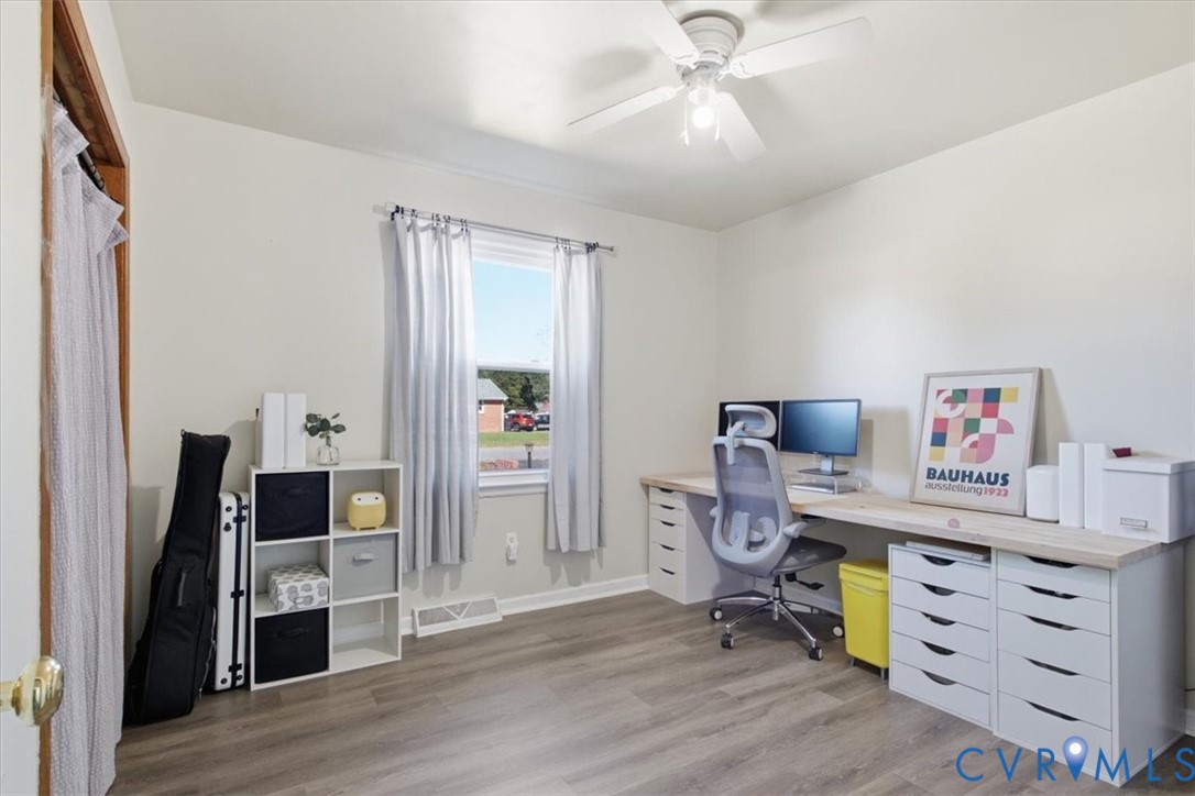 Neutral-toned room with wood-finish flooring, single-hung window, and ceiling fan with integrated light fixture