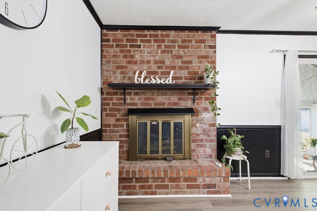 Floor-to-ceiling red brick fireplace with a built-in hearth, metal fire screen, and fixed black mantle