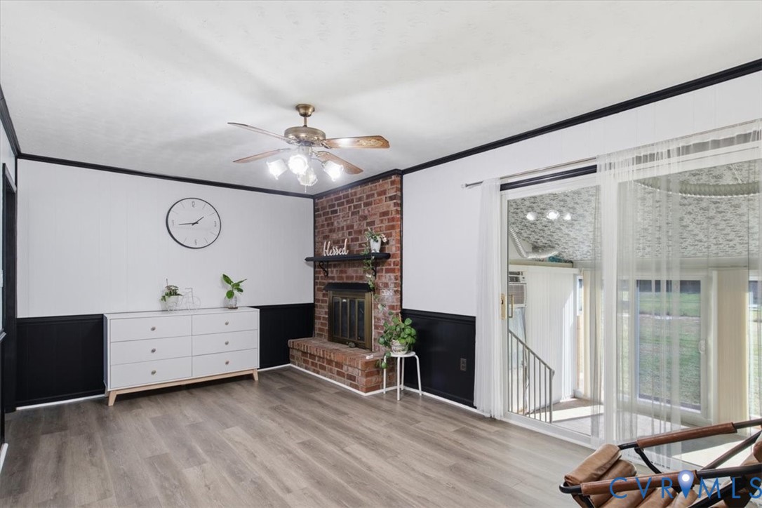 Living area featuring wood-finish flooring, a floor-to-ceiling brick fireplace with a built-in mantel, and sliding glass doors