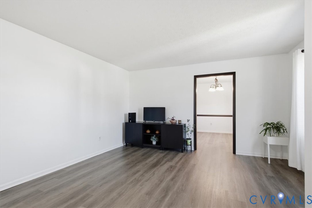 Interior space featuring wood-finish flooring, neutral walls, and a dark-toned doorway frame