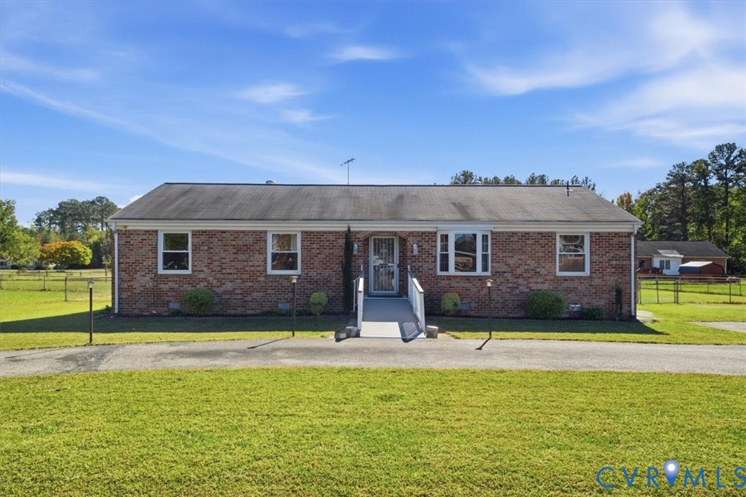 Single-story brick exterior featuring a multi-pane bay window, shingle roofing, and an asphalt driveway