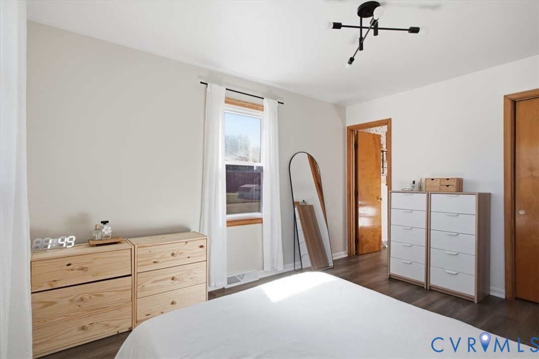 Room featuring wood-finish flooring, a multi-arm modern light fixture, and natural wood door frames
