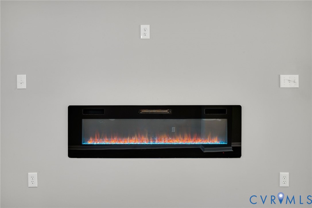 Linear electric fireplace featuring a black frame, glass front, and multi-colored ember bed Linear electric fireplace featuring a black frame, glass front, and multi-colored ember bed