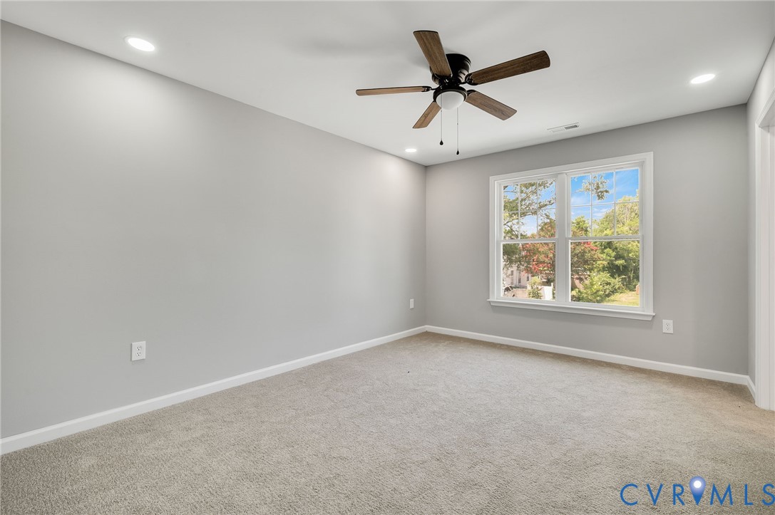 Neutral wall tones, recessed lighting, carpeted flooring, wood-finish ceiling fan, and double-pane window